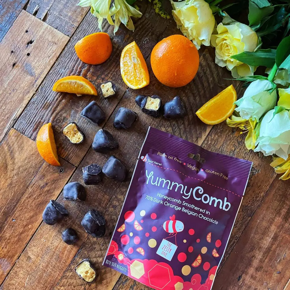 Yummcomb Dark Orange Belgian chocolate covered honeycomb nuggets pouch bags 100g with oranges on a rustic table