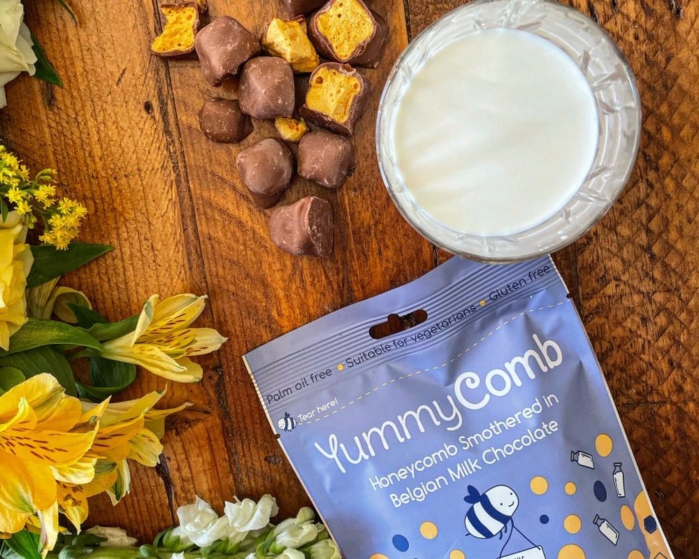Premium Belgian Milk chocolate covered honeycomb of Yummycomb pouch bags 100g scattered on a country kitchen table